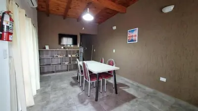 a dining room with a white table and red chairs at Cabañas La casita de las sierras in Barrio Parque El Corcovado