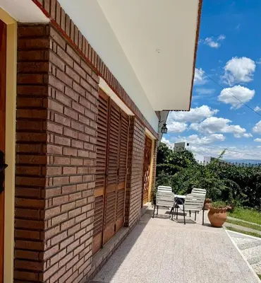 a brick building with two chairs and a table on a patio at Chalet con Piscina, a 100 m del Río, Familias in Villa Carlos Paz