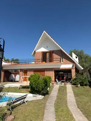 a brick house with a swimming pool in front of it at Chalet con Piscina, a 100 m del Río, Familias in Villa Carlos Paz