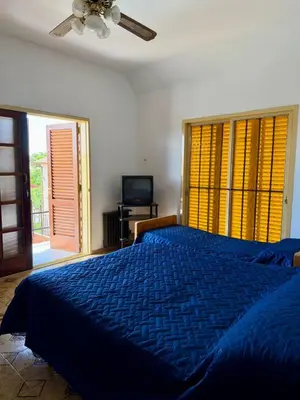 a bedroom with a blue bed and a television at Chalet con Piscina, a 100 m del Río, Familias in Villa Carlos Paz