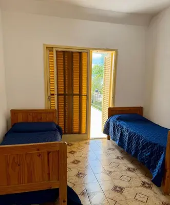 two beds in a room with a door to a balcony at Chalet con Piscina, a 100 m del Río, Familias in Villa Carlos Paz