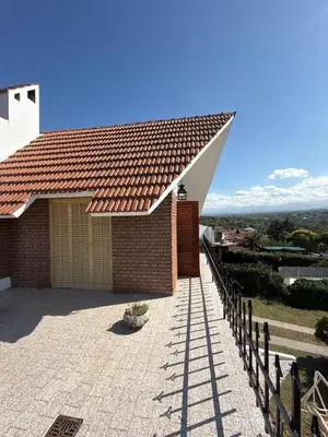a house with a roof with a fence at Chalet con Piscina, a 100 m del Río, Familias in Villa Carlos Paz