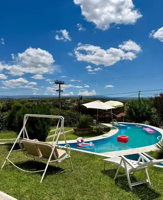 a yard with two chairs and a swimming pool at Chalet con Piscina, a 100 m del Río, Familias in Villa Carlos Paz