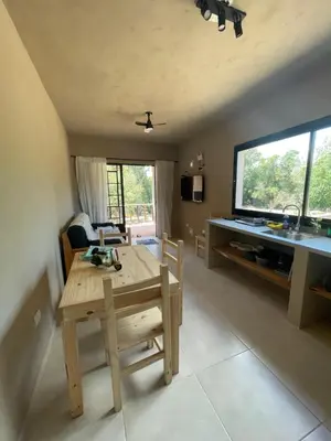 a living room with a wooden table and a television at Cabañas Arenas del Panaholma in Villa Cura Brochero