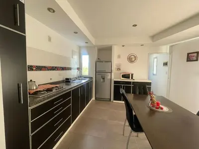 a kitchen with black cabinets and a table and a refrigerator at Lo de coco in Villa Cura Brochero