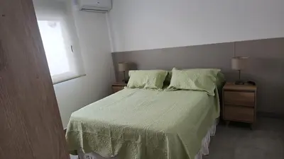 a bedroom with a bed with green sheets and a window at Departamento macrocentro I, espacioso Río Cuarto in Río Cuarto