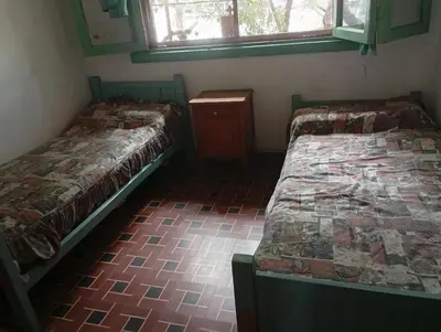 a room with two beds and a table and windows at Departamento Temporario y Complejo Habitacional in Villa Carlos Paz