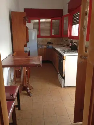 a kitchen with red cabinets and a white refrigerator at Departamento Temporario y Complejo Habitacional in Villa Carlos Paz