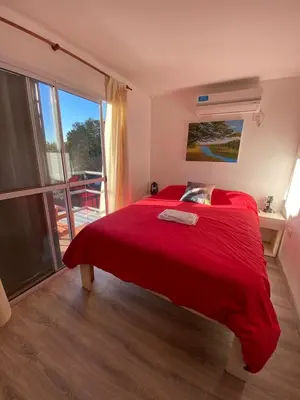 a bedroom with a red bed and a large window at EcoBox in Despeñaderos