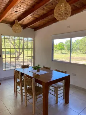 a dining room with a wooden table and chairs at Cabaña La Querencia in Piedras Blancas