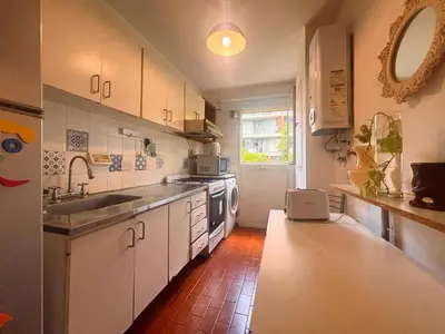 a kitchen with white cabinets and a sink and a counter at Depto Victoria in Cordoba