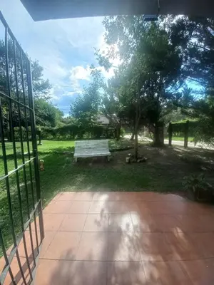 a park bench sitting in the grass near a tree at Tantanakuy 4 in Villa General Belgrano