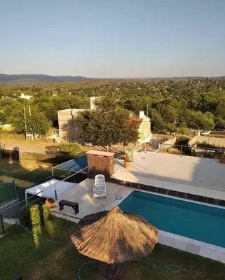 a swimming pool with a straw umbrella and a table at paraíso lomas in San Antonio de Arredondo