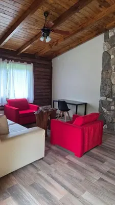 a living room with red furniture and a stone wall at Paraiso en el Manantial in Villa General Belgrano