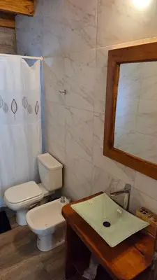 a bathroom with a toilet and a sink and a mirror at Paraiso en el Manantial in Villa General Belgrano