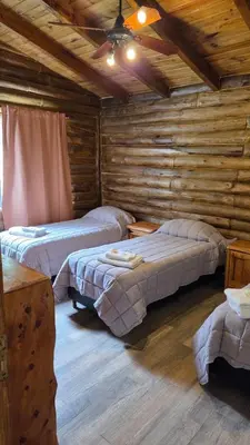 a room with two beds in a log cabin at Paraiso en el Manantial in Villa General Belgrano