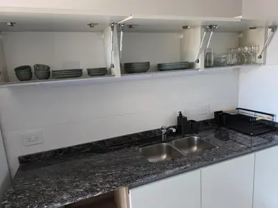 a kitchen counter with a sink and plates on a shelf at Opera Park en Barrio Las Rosas in Cordoba