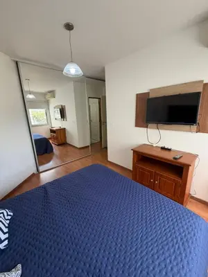 a bedroom with a blue bed and a flat screen tv at Depto Carillo 4p in Villa Carlos Paz