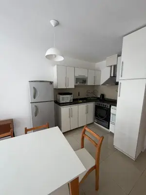 a kitchen with a table and a white refrigerator at Depto Carillo 4p in Villa Carlos Paz
