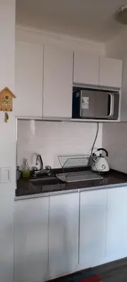 a white kitchen with a sink and a microwave at Departamento con salida a la peatonal! in Villa Carlos Paz
