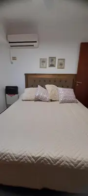 a large white bed with two pillows on it at Departamento con salida a la peatonal! in Villa Carlos Paz