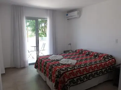 a bedroom with a bed with a red blanket and a window at Hotel Pinar del Lago in Villa Carlos Paz