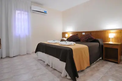 a bedroom with a bed and a table with towels on it at Hotel Pinar del Lago in Villa Carlos Paz
