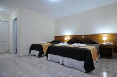 a hotel room with two beds and two tables at Hotel Pinar del Lago in Villa Carlos Paz