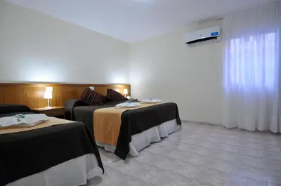 a hotel room with two beds and a window at Hotel Pinar del Lago in Villa Carlos Paz