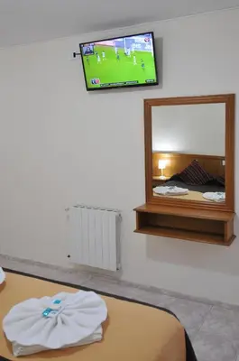 a room with a tv and a bed and a mirror at Hotel Pinar del Lago in Villa Carlos Paz