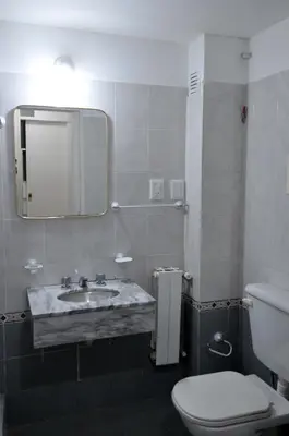 a bathroom with a sink and a toilet and a mirror at Hotel Pinar del Lago in Villa Carlos Paz