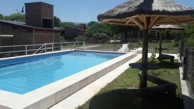 a swimming pool with an umbrella and a chair and a table at Rio De Arena in Nono