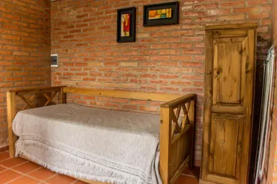 a bedroom with a bed and a brick wall at Rio De Arena in Nono