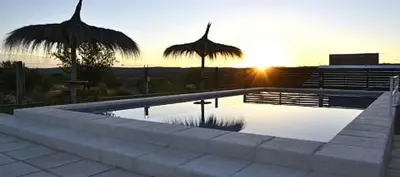 a swimming pool with a sunset in the background at Rio De Arena in Nono