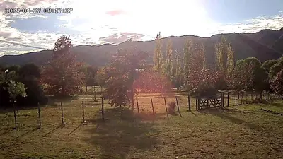 a field with a fence and trees and mountains at Mutterstern Chalet Boutique in Villa General Belgrano