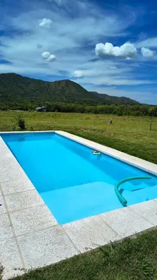 a large blue swimming pool in a field at Mutterstern Chalet Boutique in Villa General Belgrano