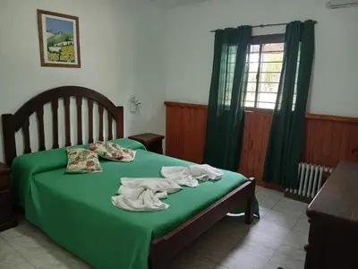 a bedroom with a bed with green sheets and a window at Colores de Traslasierra in Mina Clavero