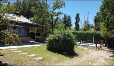 a yard with a bush and a house and a pool at Colores de Traslasierra in Mina Clavero
