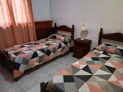 a bedroom with two beds and a lamp on a night stand at Colores de Traslasierra in Mina Clavero