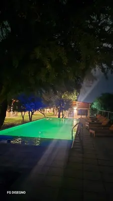 a green swimming pool at night with trees and benches at Ilusión tunkelen in Merlo