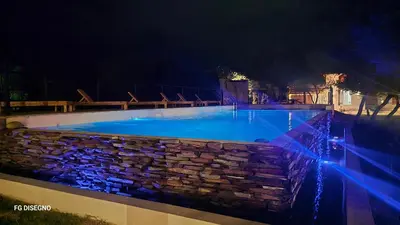 a swimming pool with a stone wall and blue lights at Ilusión tunkelen in Merlo