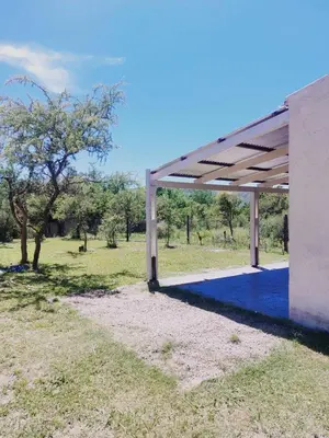 a white building with a roof over a field at Cabañas EL VALLE in Villa Rumipal
