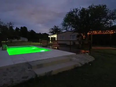 a green pool in a backyard at night at Cabañas EL VALLE in Villa Rumipal
