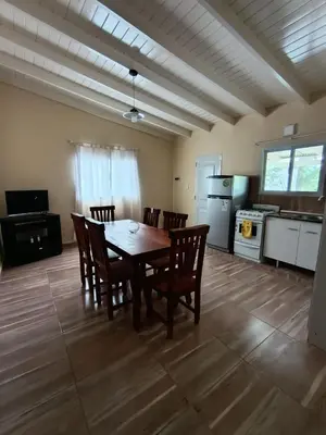 a dining room with a table and chairs and a kitchen at Cabañas EL VALLE in Villa Rumipal