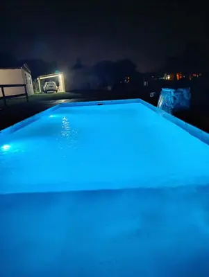 a swimming pool lit up with blue lights at night at Cabañas EL VALLE in Villa Rumipal