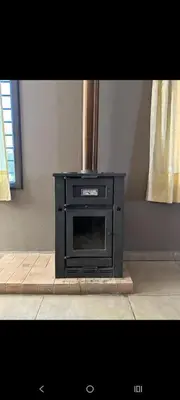 a fireplace in a living room with a stove at Sueños Del Valle in Villa Anizacate