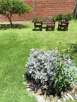 a garden with two benches and flowers in the grass at Tu Escapada in Santa María