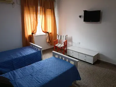 a bedroom with two beds and a tv and a chair at Deptos Charito in Cordoba