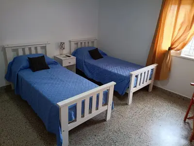 two beds in a bedroom with blue sheets and a window at Deptos Charito in Cordoba