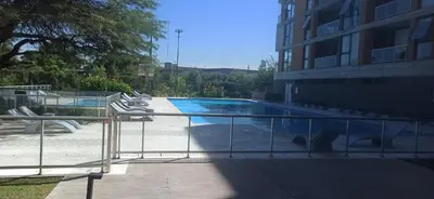 a swimming pool with chairs next to a building at Hermoso Departamento en Opera Plaza al lado de Quality Espacios in Cordoba